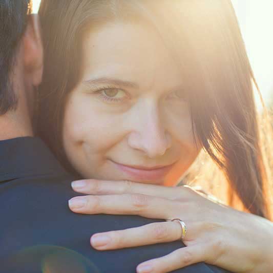 Žena se snubním prstenem objímá muže